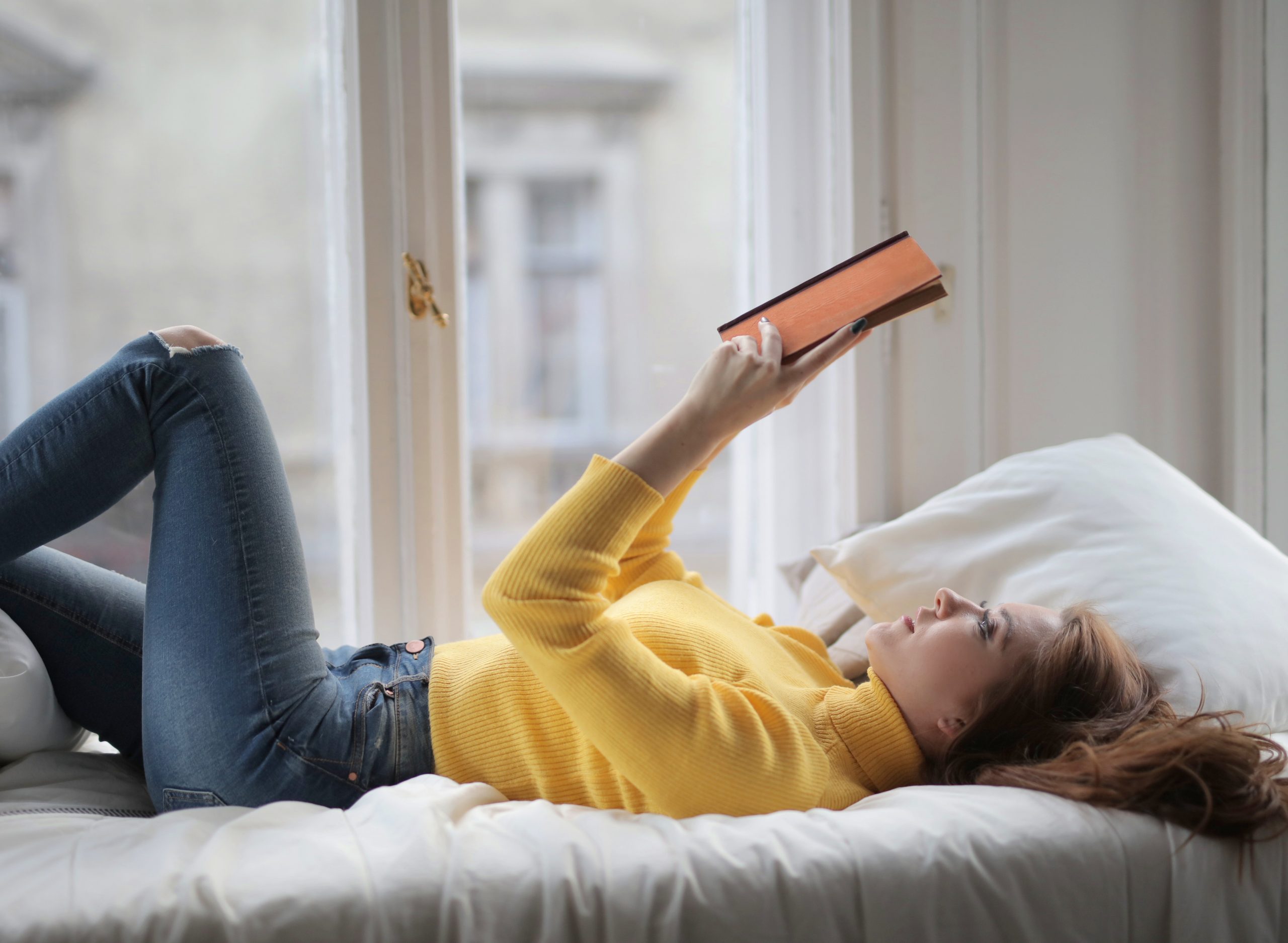 woman reading book in bed